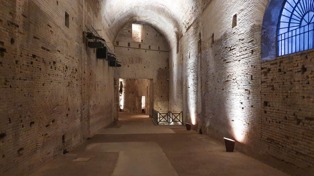 The lit-up entrance to the Domus Aurea building with arched ceiling and lanterns