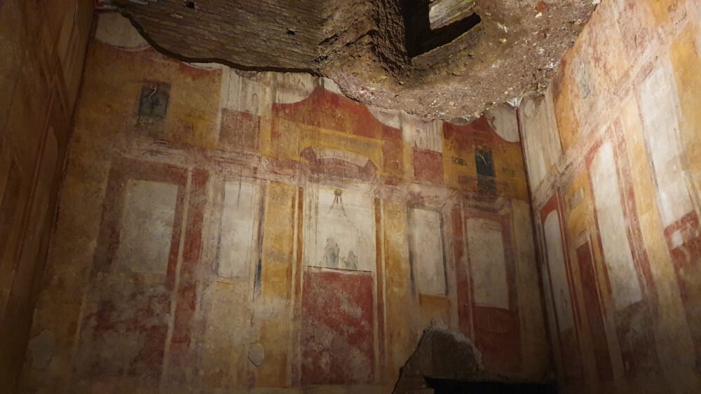 Fresco paintings on the walls in the Grotesque style with lots of red, yellow, detailed work