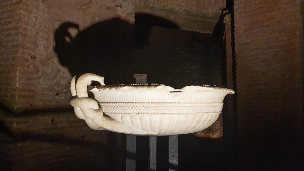 A decorative vase within the Domus Aurea complex displayed in the low light of the underground site