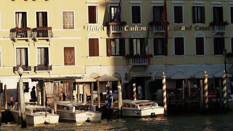 Light falling on the Hotel Carlton on the Grand canal with gondolas and boats in front