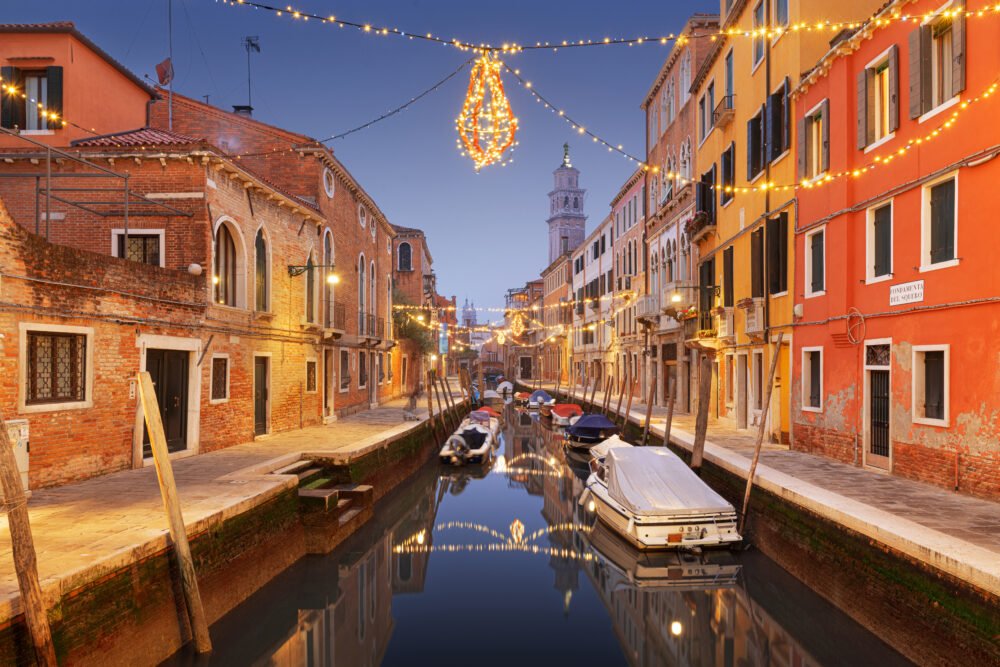 Venice, Italy cityscape over canals at twilight with Christmas lights, as you might see while touring on a gondola