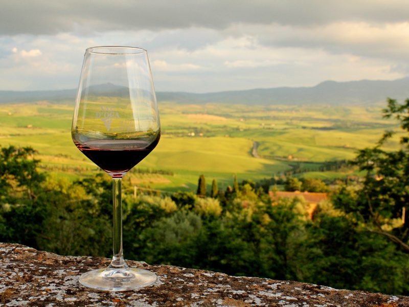 glass of wine with tuscan countryside in the background