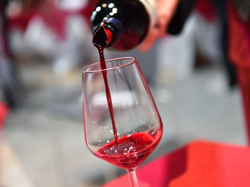 A Super Tuscan wine being poured into a clear wine glass