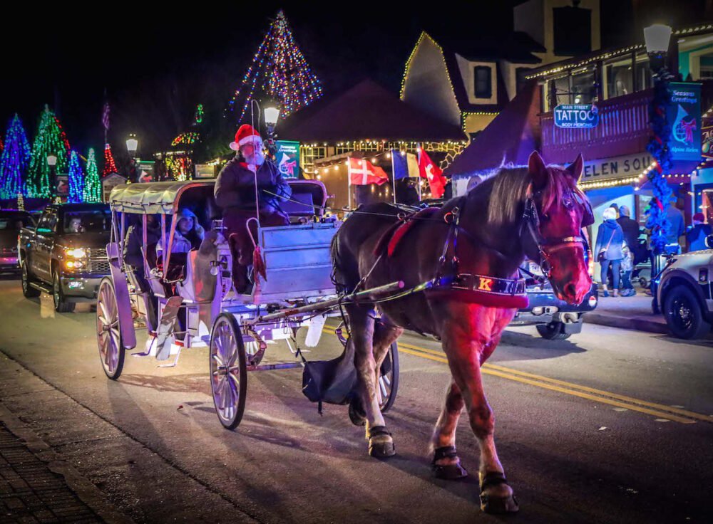 Horse pulling a Christmas carriage with festive lights in the background in Helen, Georgia, a popular US December travel destination