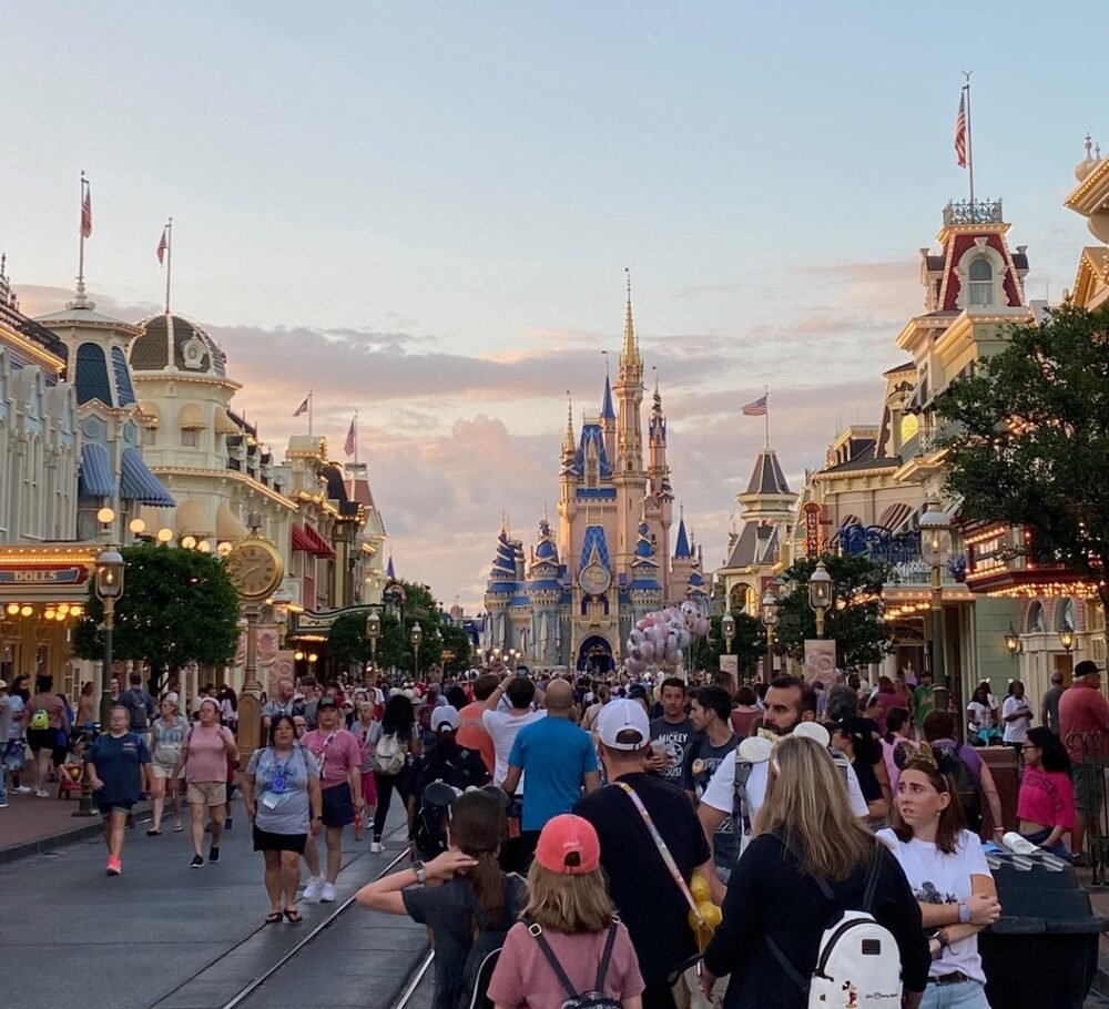 Crowd of people enjoying Disneyworld in January in the USA. Castle and rides visible in the background.