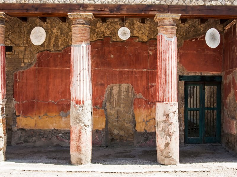 View of red painted walls and pillars inside while visiting herculaneum site