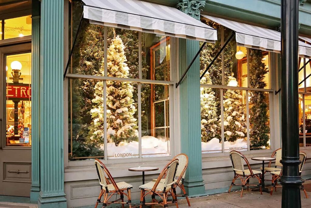 Christmas tree in a cafe with bistro style seating with Parisian looking chairs and round tables for outdoor seating