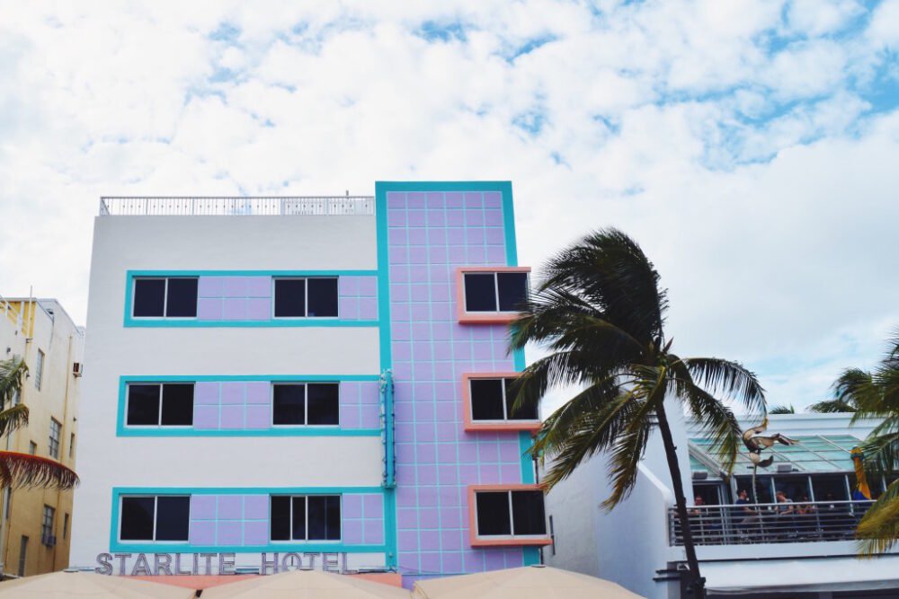 Colorful Miami beachside building with palm tree, restaurant bar on the beach, and other views
