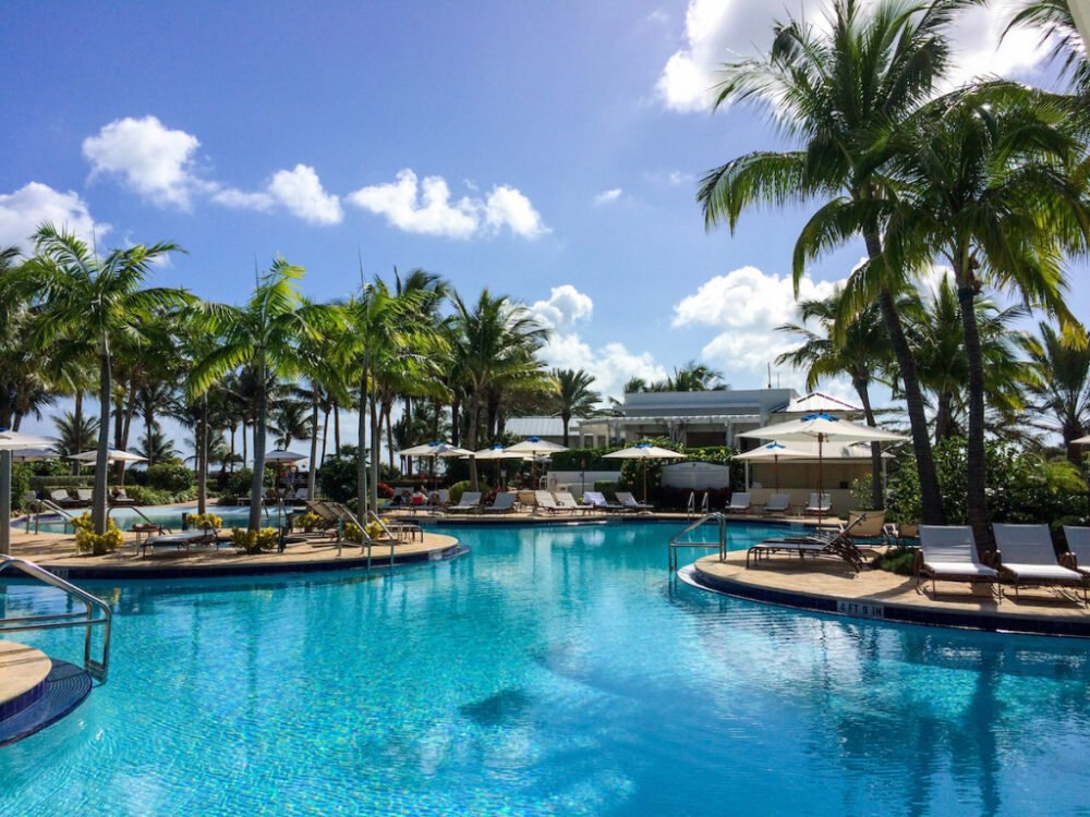 Pool area in a Miami hotel with palm trees, clouds, lounge chairs on a warm day in the winter in the USA