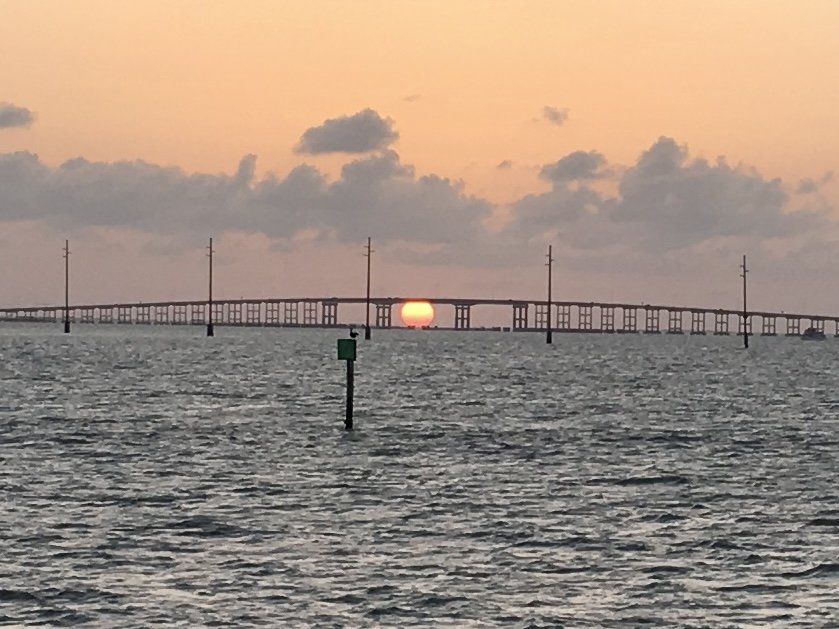 The sun setting low on the horizon over the water, underneath a bridge, on South Padre Island in Texas, a great warm winter getaway in the USA