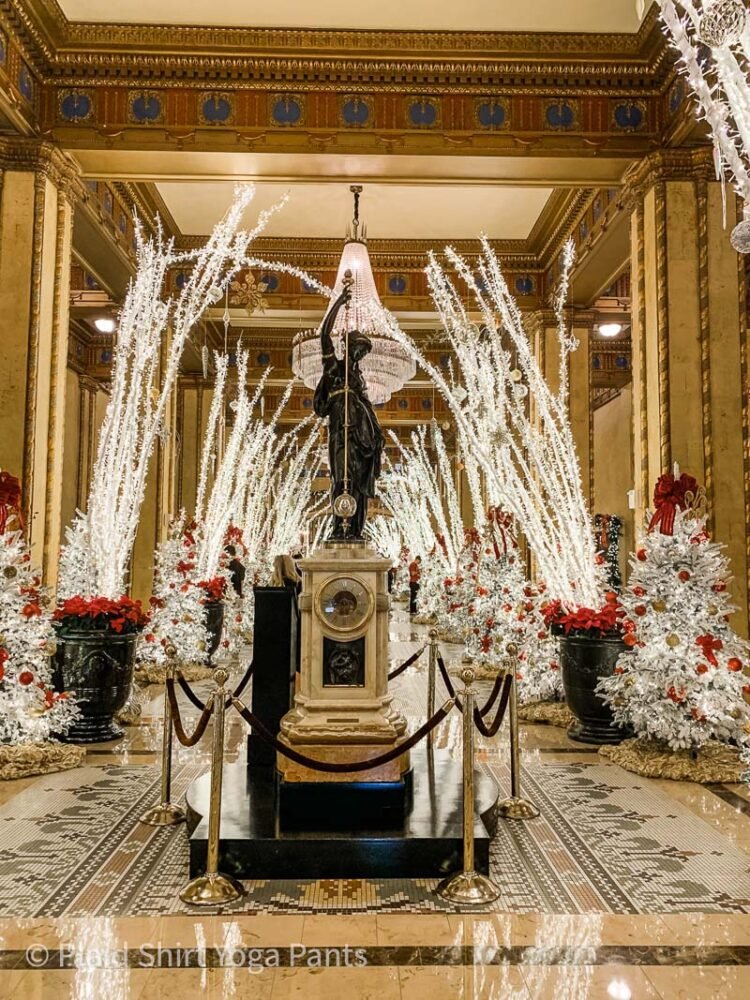 The interior of the Roosevelt New Orleans - a statue with ornate christmas trees and other lit up decoration in an ornate building