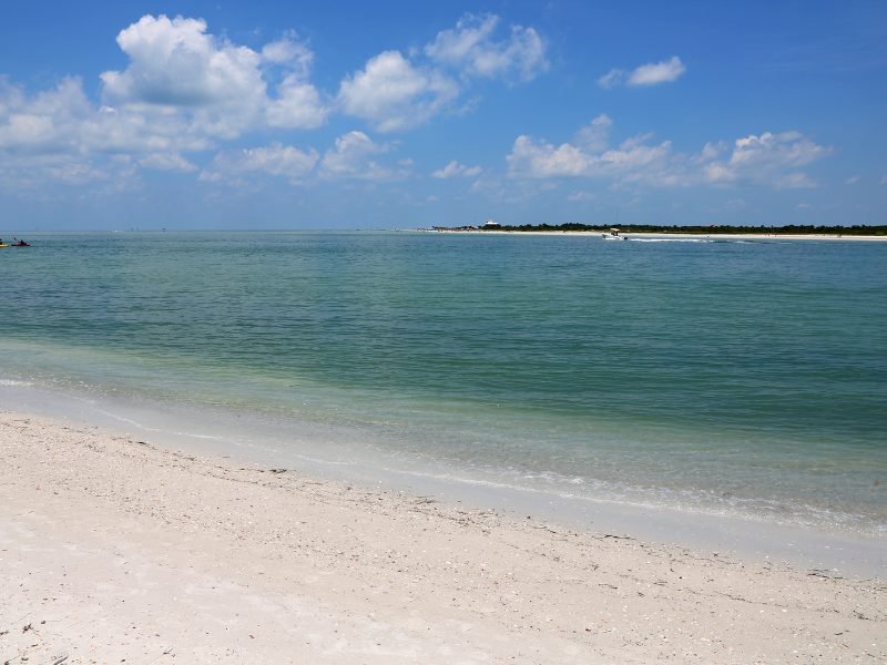 The view from Caladesi Island with soft white sand, brilliant blue water, and a boat on the water in the distance