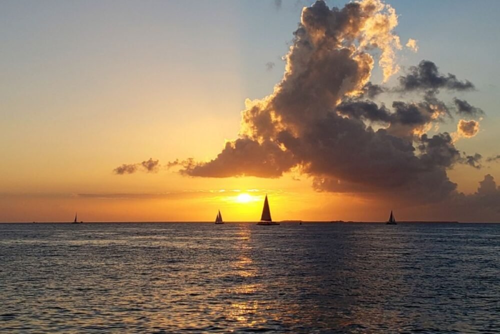 View of the sunset with sailboats on the horizon and dramatic clouds in Key West FL a popular warm winter getaway in the USA