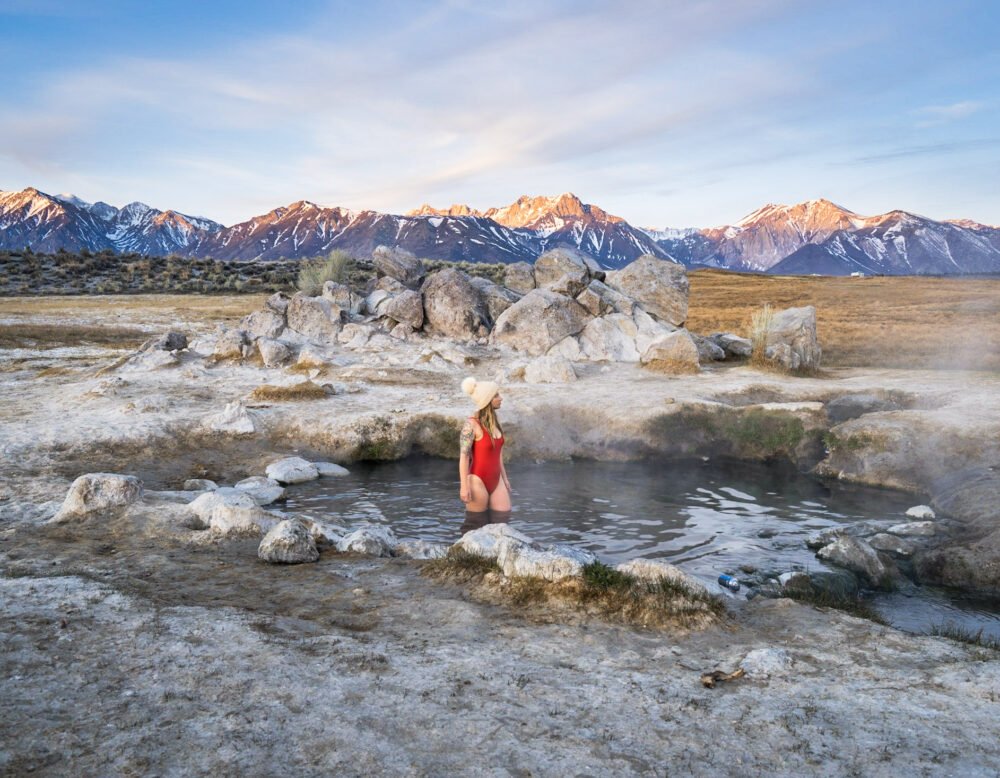 Person in a red bathing suit in a natural hot spring in the snowy countryside