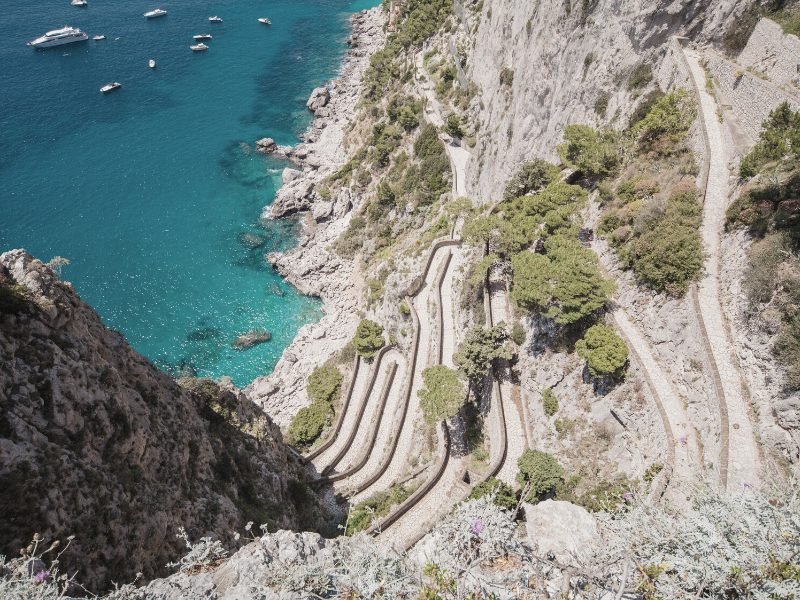 The hairpin turns down a really steep cliff leading down to the water in Capri winding downwards, view from above