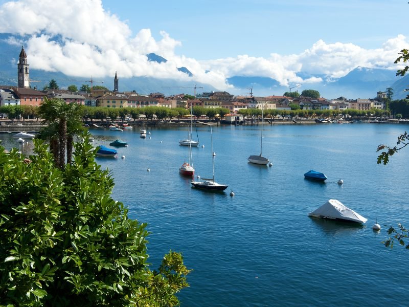 boats on the water with houses along the lakeshore in a lakeside town in italy