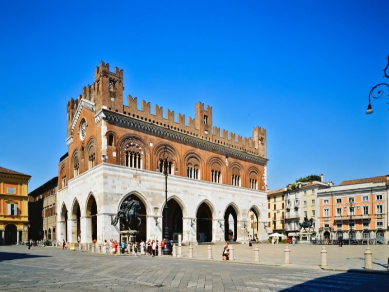 marble and stonework archway with red brick on top in a building in the center of a piazza in placenta italy