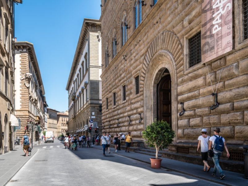 People walking in front of Palazzo Strozzi in Florence, Italy on a sunny summer day