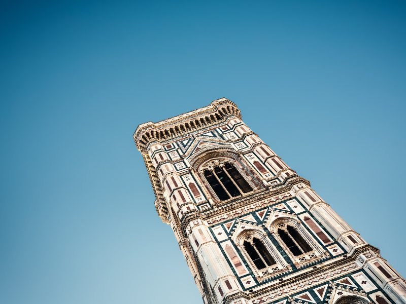 View looking up at the ornate architecture and windows on the Giotto Tower in florence on a clear sunny day.