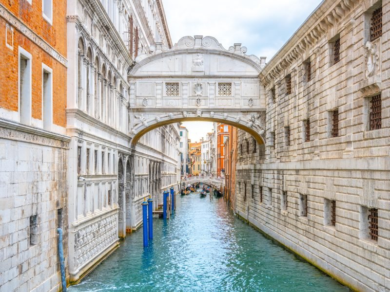 A high bridge connecting two buildings in Venice over a canal