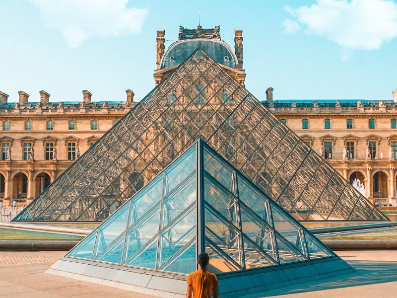 Symmetrical views of the two pyramids in front of the Louvre, with the Louvre behind it