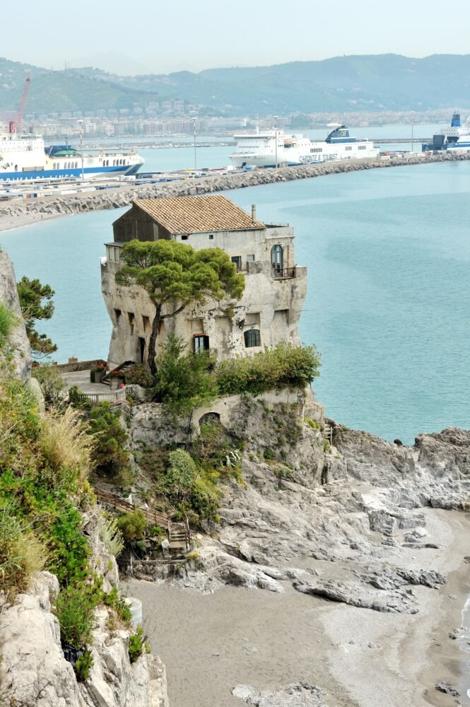 A view of Crestarella tower, an old tower or villa in Vietri sul Mare, in Amalfi coast, with beach and beautiful sea view with ships etc in the background