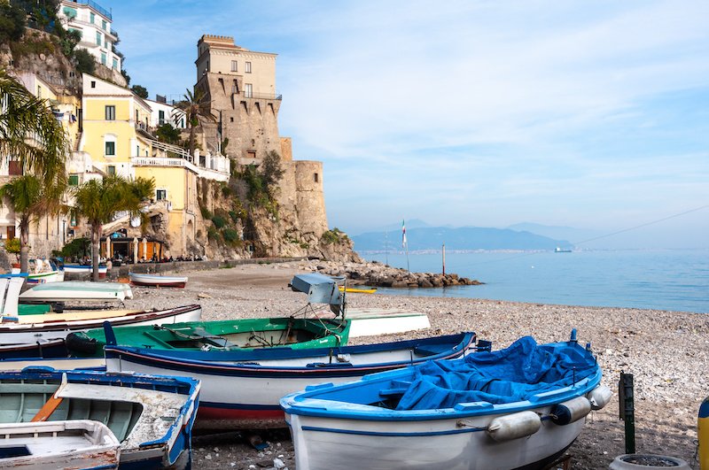 Beach with boats and a tower in the background on the Amalfi Coast