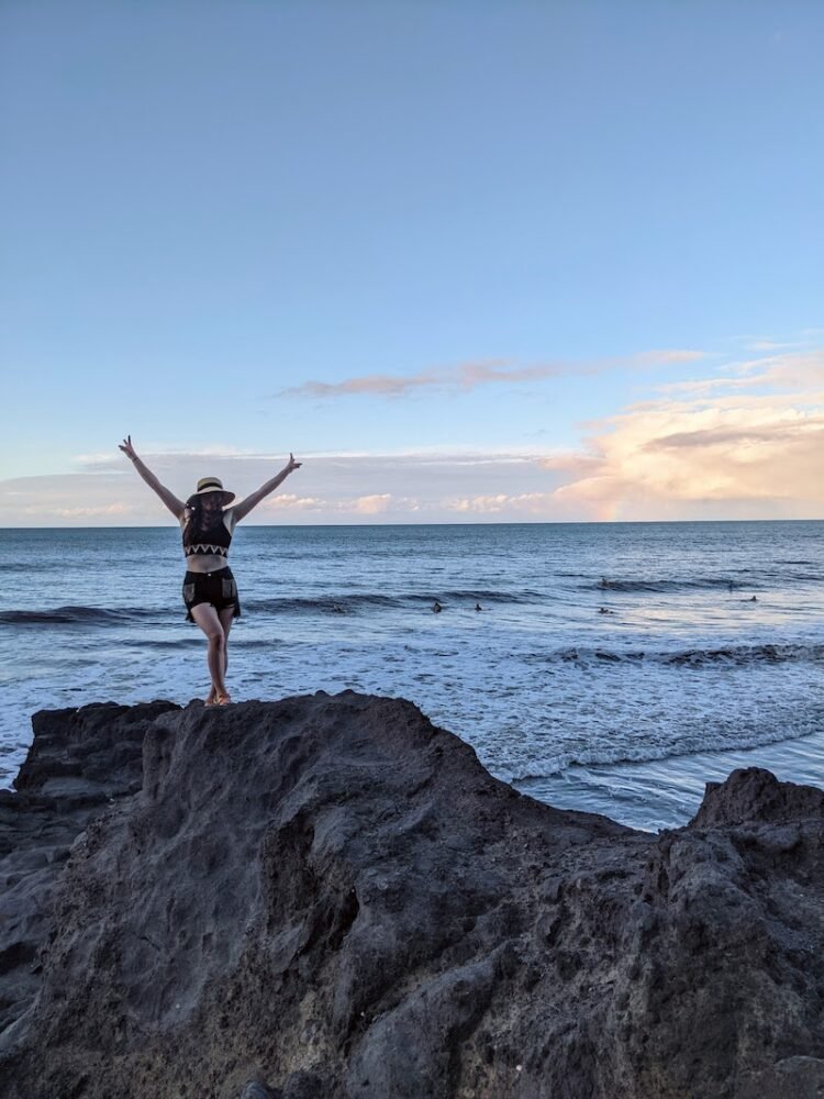 Allison standing on a rock with her arms up in the air