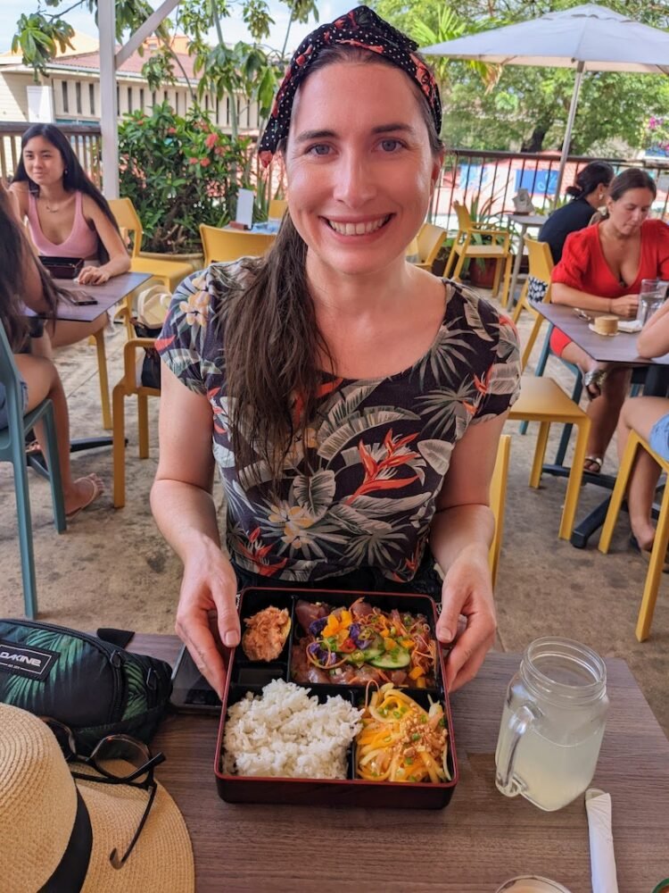 Allison eating food in a restaurant in a green tropical print top