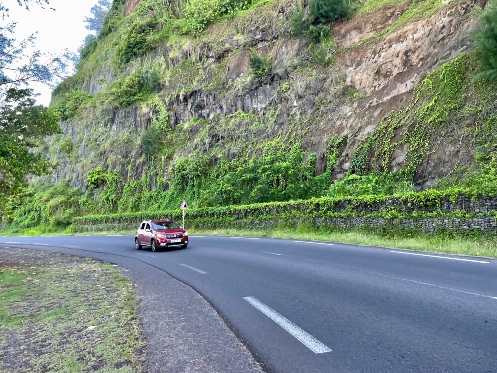 Coastal road with a red car on it on Tahiti