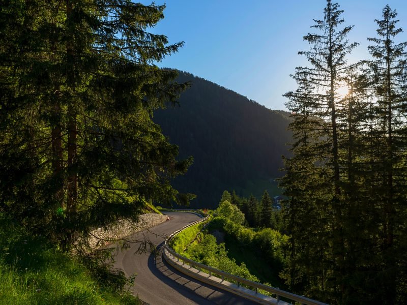 Small, winding road going through the mountains in the Dolomites as the sun starts to set