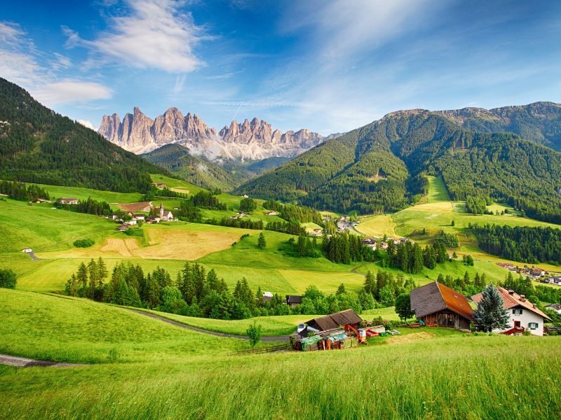 Val di Funes with background of mountains and snow and beautiful small towns and churches in the distance