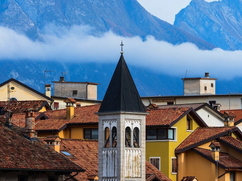 Tower and buildings and mountains in the town of Belluno with late afternoon light