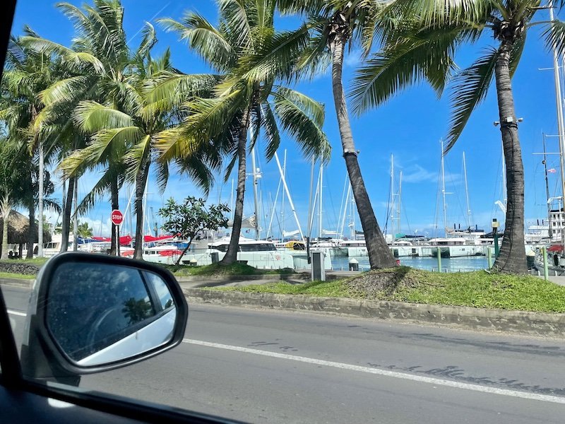 Looking out the rearview mirror with passing sailboats in Tahiti while driving