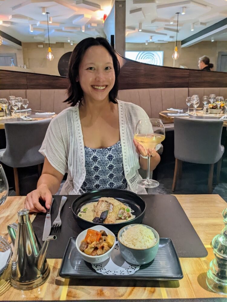 Allison's partner enjoying a delicious seafood dinner in Papeete and holding up a glass of wine