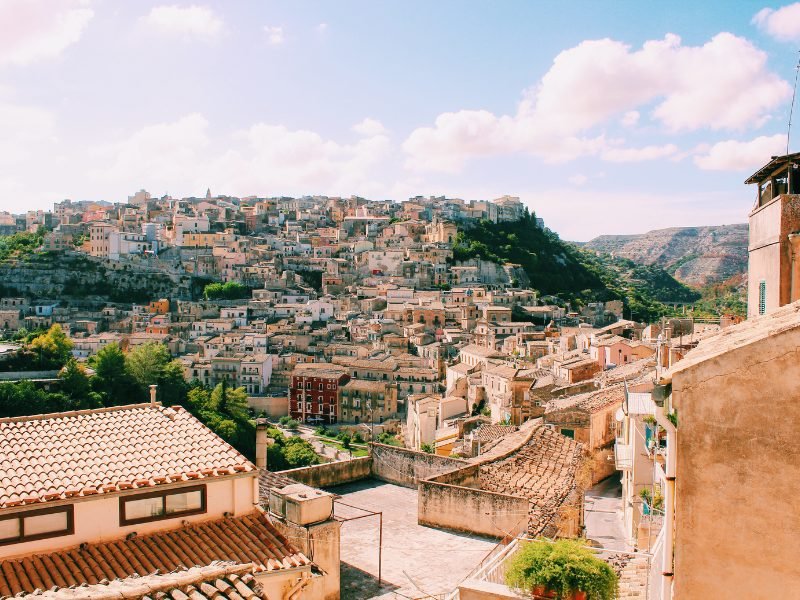 The hilltop city of Ragusa Sicily with views over the hills undulating with buildings and cloudy sky