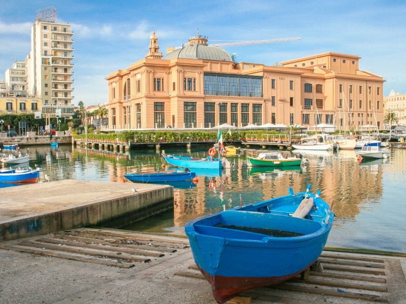 Famous coral-pink building in Bari with boats in small harbor in the city center