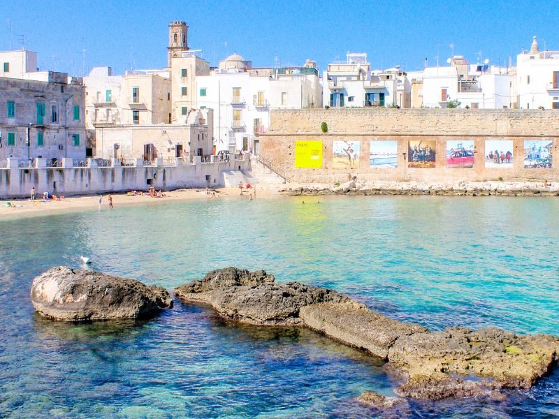 Beach in Monopoli Italy with blue water and whitewashed buildings in background