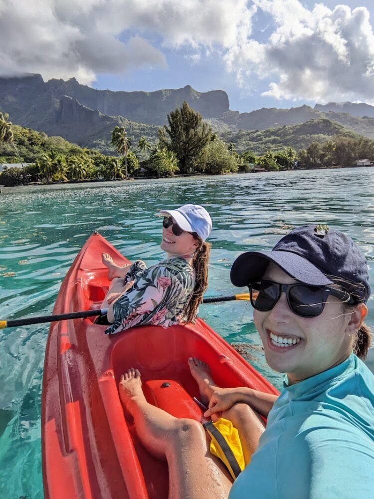 Allison and her partner in a red kayak with the island of Moorea behind them and brilliant blue waters