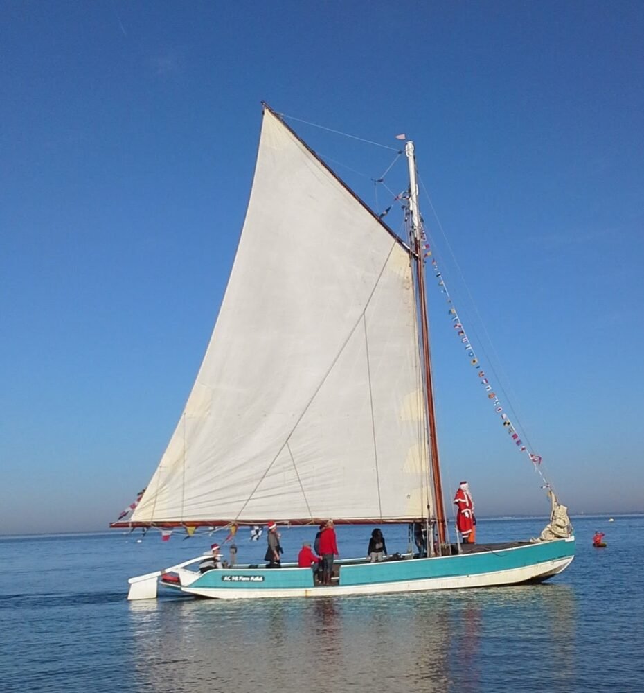 Santa on a boat in the Atlantic ocean with calm water and boat decorated with flags and festive decorations