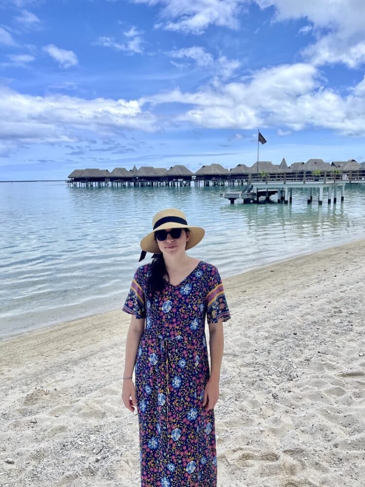 Allison in a sunhat and colorful flower print maxi dress in front of the Sofitel Bungalows