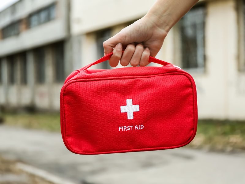 Small red first aid kit with a white cross plus sign on it