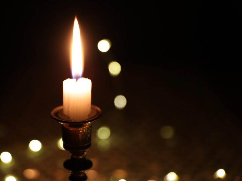 close up of a lit candle with blurry bokeh background of other lights