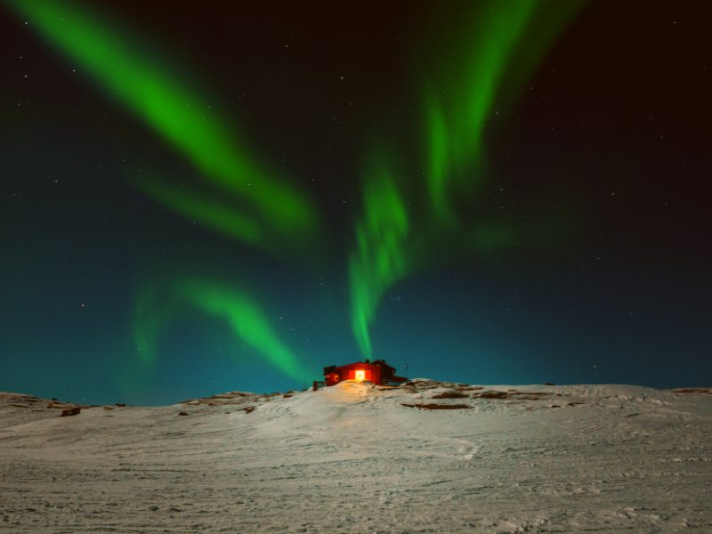 The northern lights over Abisko with the sky station on a hill 