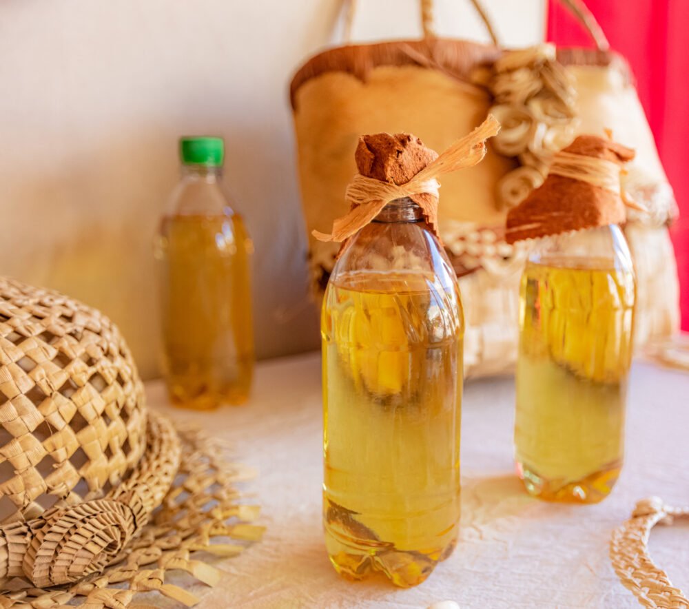 Tahitian monoi oil, handmade and in a bottle with ribbon, next to hand woven hat