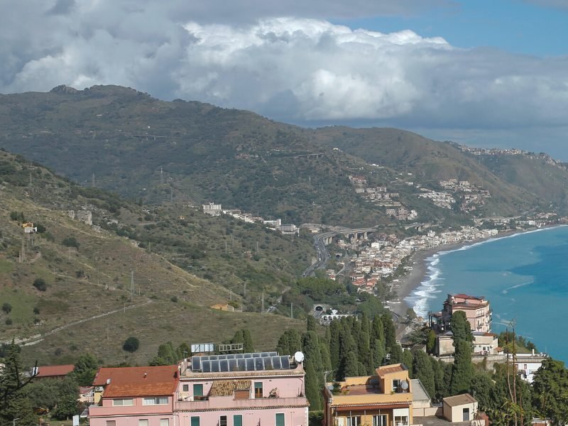 A sandy beach as seen from up above on a vantage point in the Taormina town, looking down onto Spiaggia di Spisone below