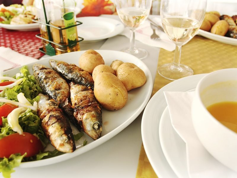 Typical Portuguese meal of grilled sardines, potatoes and salad with white wine and soup