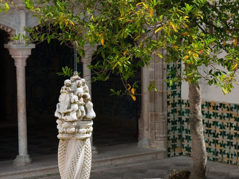 Statue in the interior courtyard of the national palace of sintra, with archways and mosaic on the walls