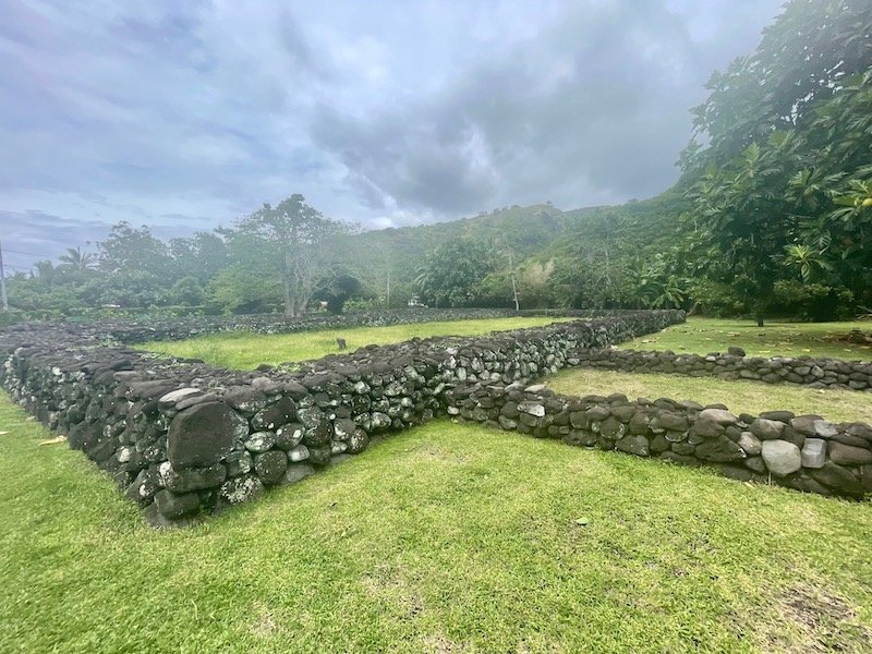 An ancient set of ruins made of rocks that are joined together perfectly so they do not fall, on a cloudy, misty day in Tahiti