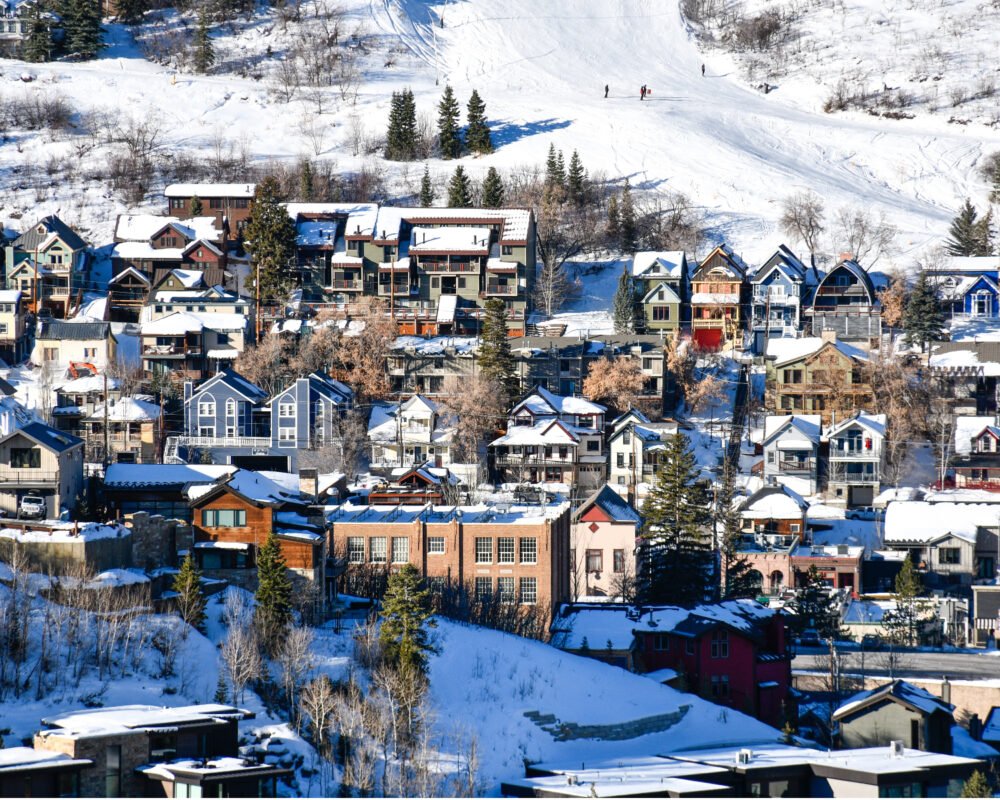 View of accommodations in the Park city, utah area with people on the ski slopes behind the houses and resorts